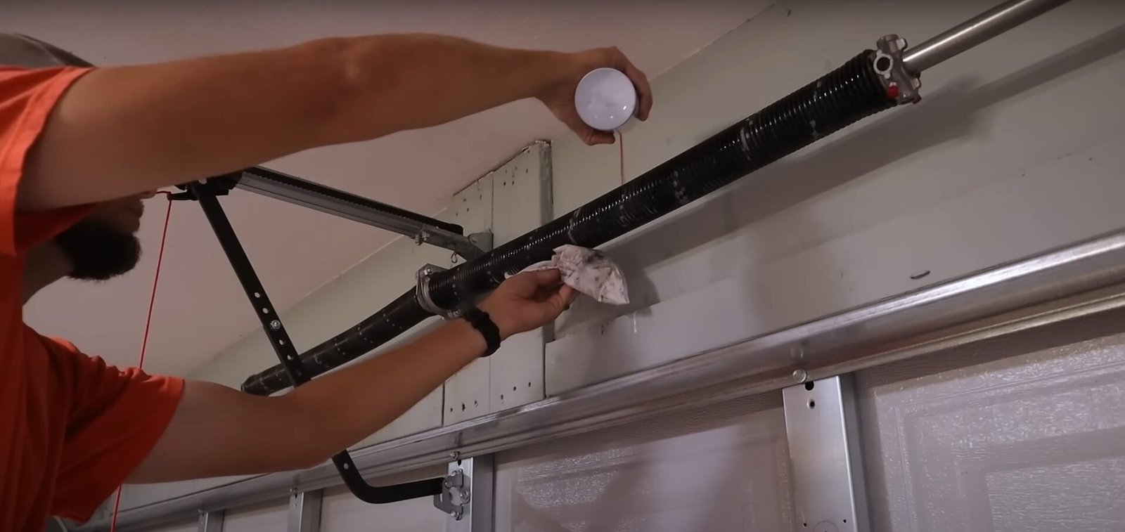 Lubricating garage door spring to fix noisy garage door.