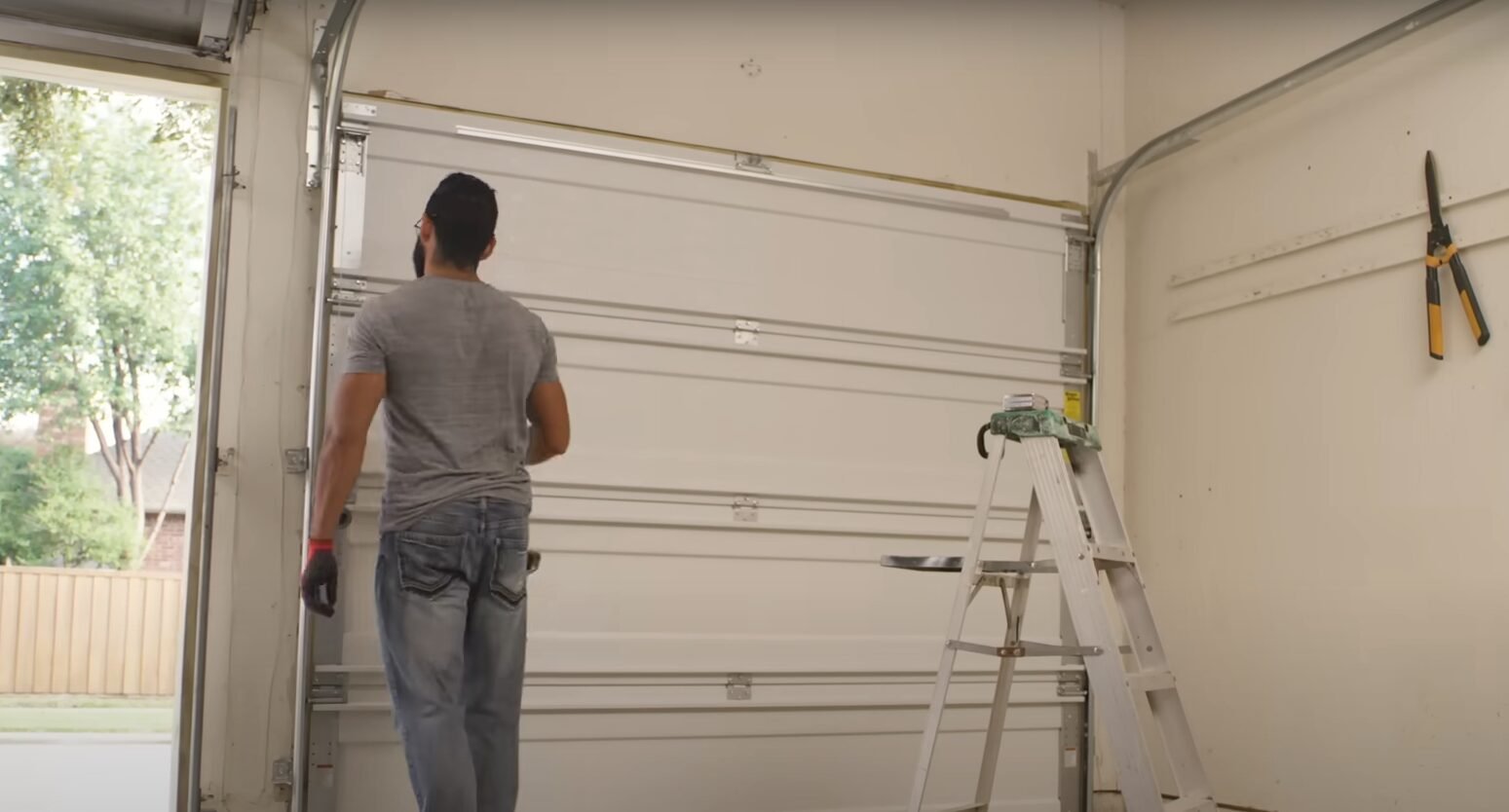 A skilled technician from Powell Garage Door Repair working on a garage door spring replacement, ensuring safety and precision